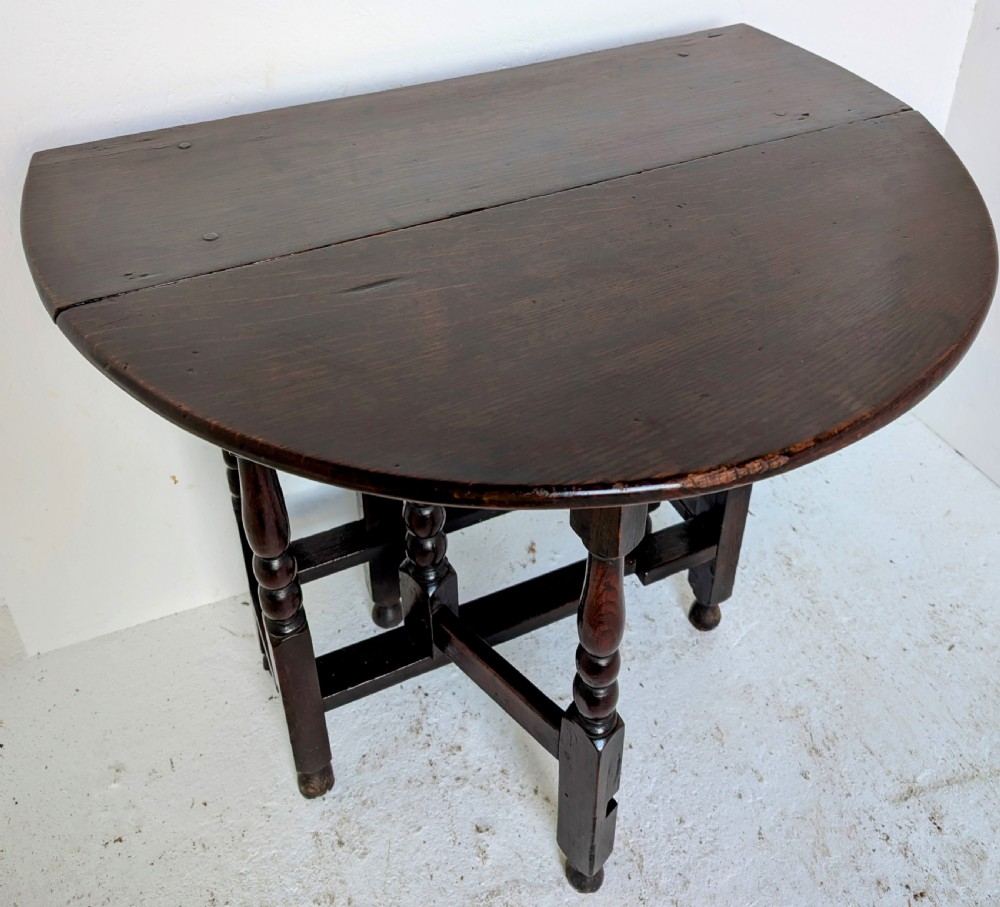 A dark oak 17th-century gateleg table with two drop-leaf flaps, turned baluster legs, and low box stretchers. View IX