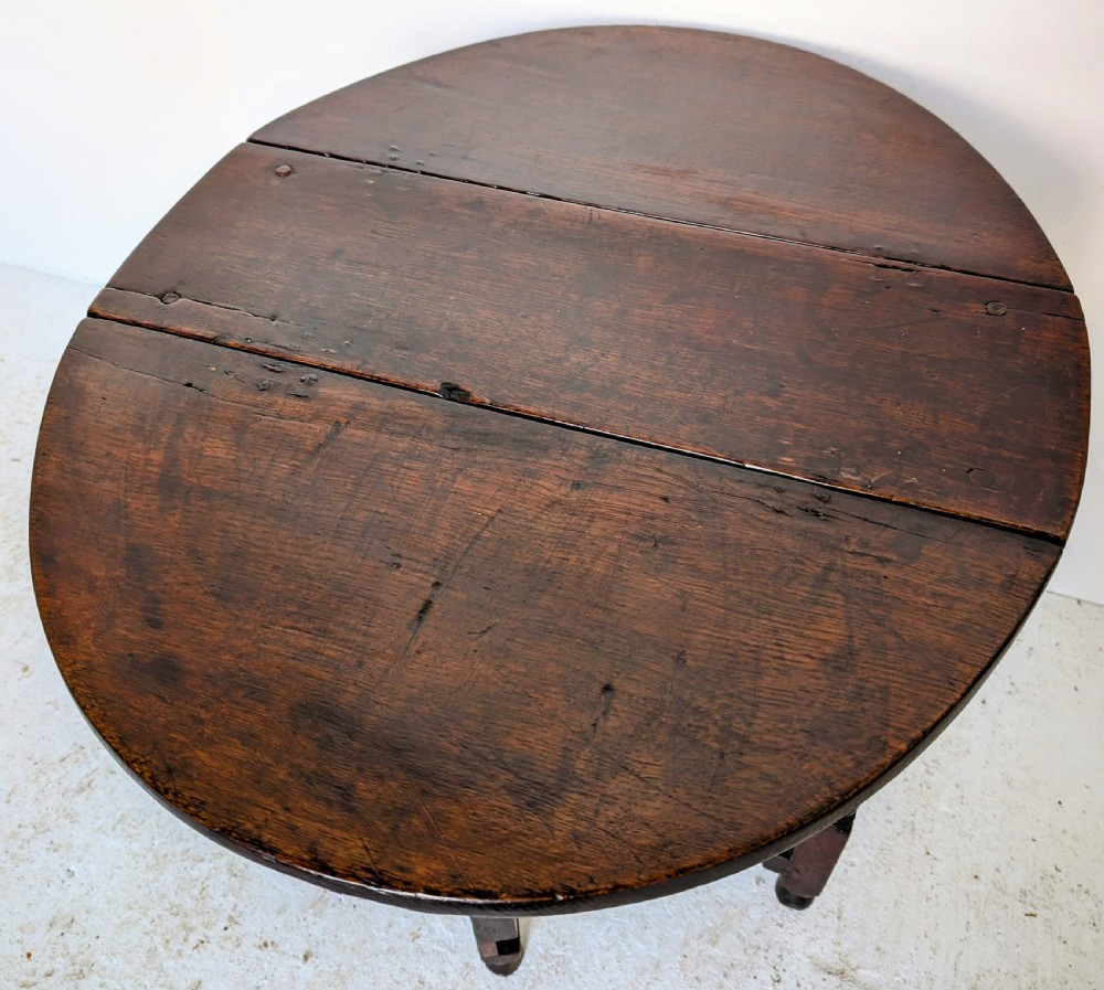 A dark oak 17th-century gateleg table with two drop-leaf flaps, turned baluster legs, and low box stretchers. View XI