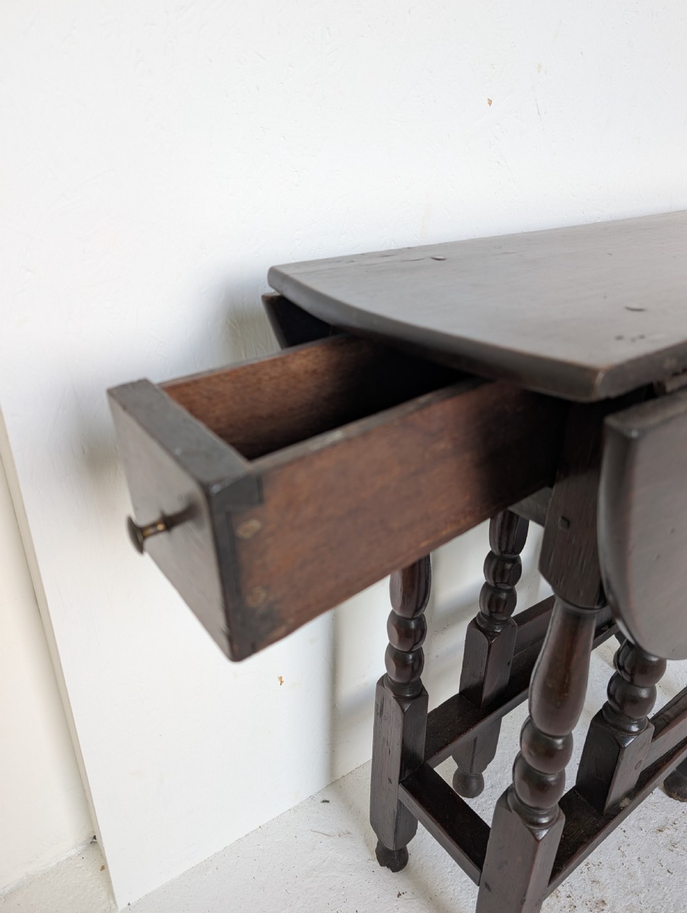 A dark oak 17th-century gateleg table with two drop-leaf flaps, turned baluster legs, and low box stretchers. View XIII