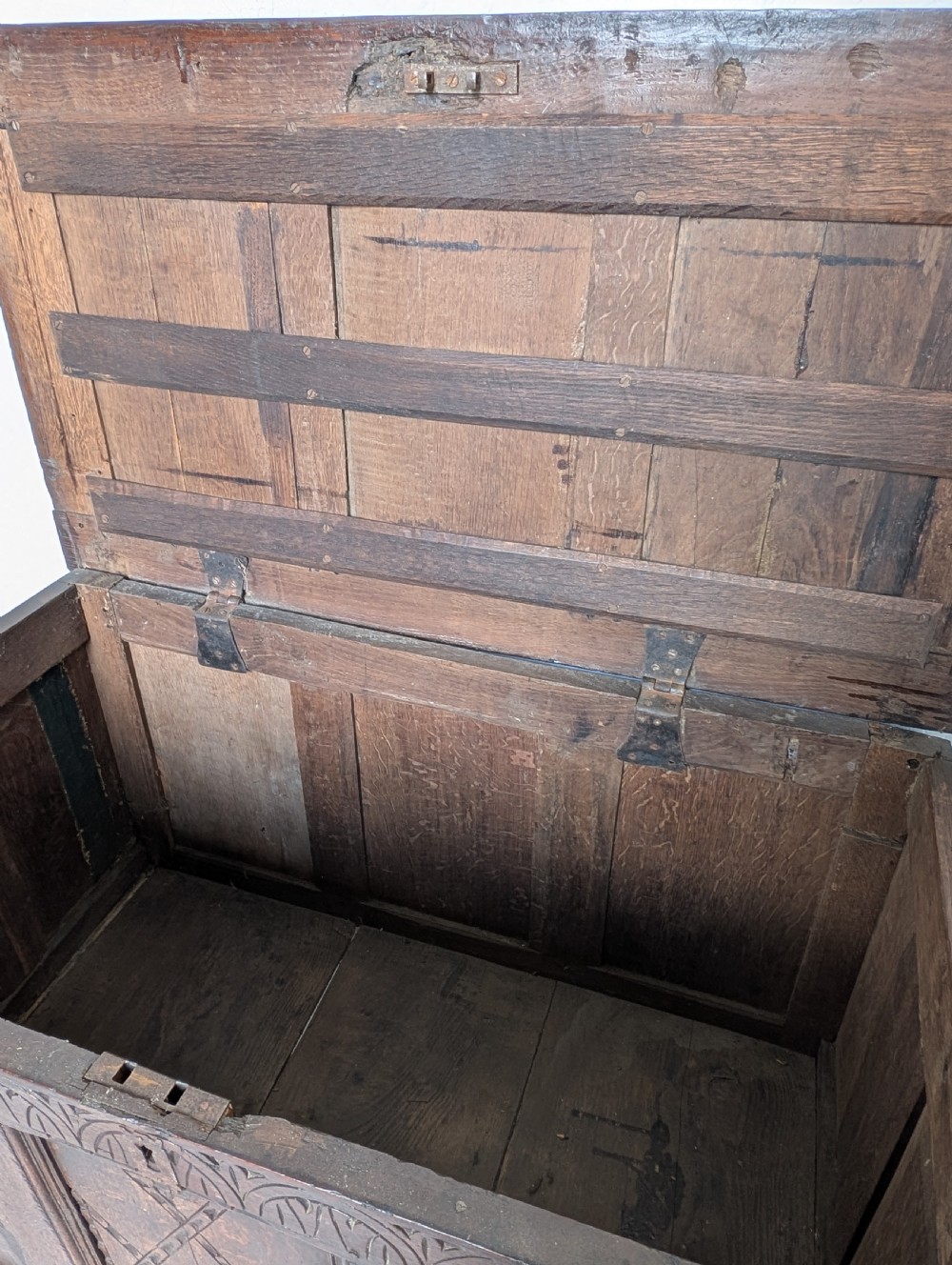 A 17th-century dark carved oak coffer featuring a three-panel hinged top and carved geometric patterns on the front panels. View III
