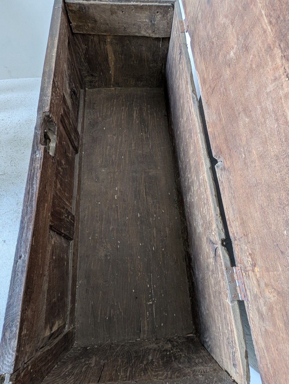 A dark brown 17th century oak coffer featuring three carved panel fronts with circular rosette motifs and a hinged lid. View IV