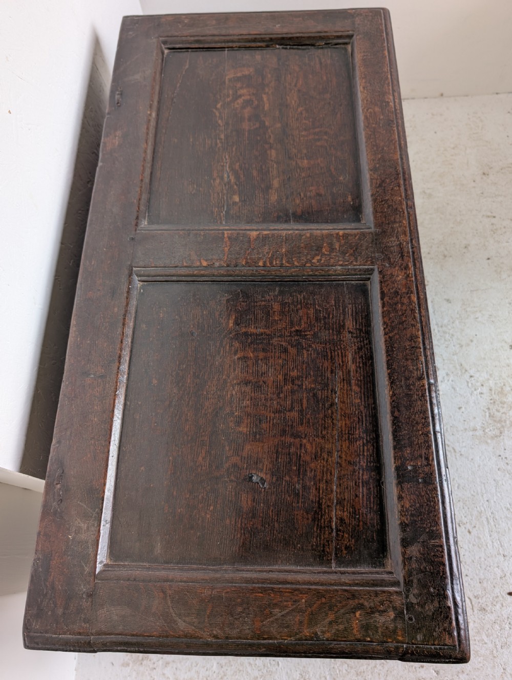 A 17th-century dark oak coffer featuring lunette carving on the upper rail and lozenge panel detailing across the front. View V