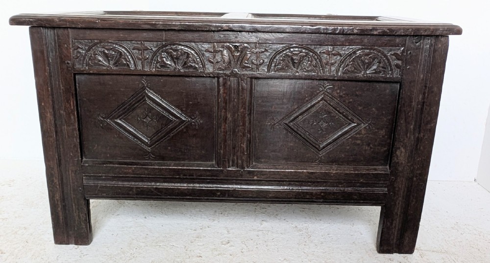 A 17th-century dark oak coffer featuring lunette carving on the upper rail and lozenge panel detailing across the front. View IX