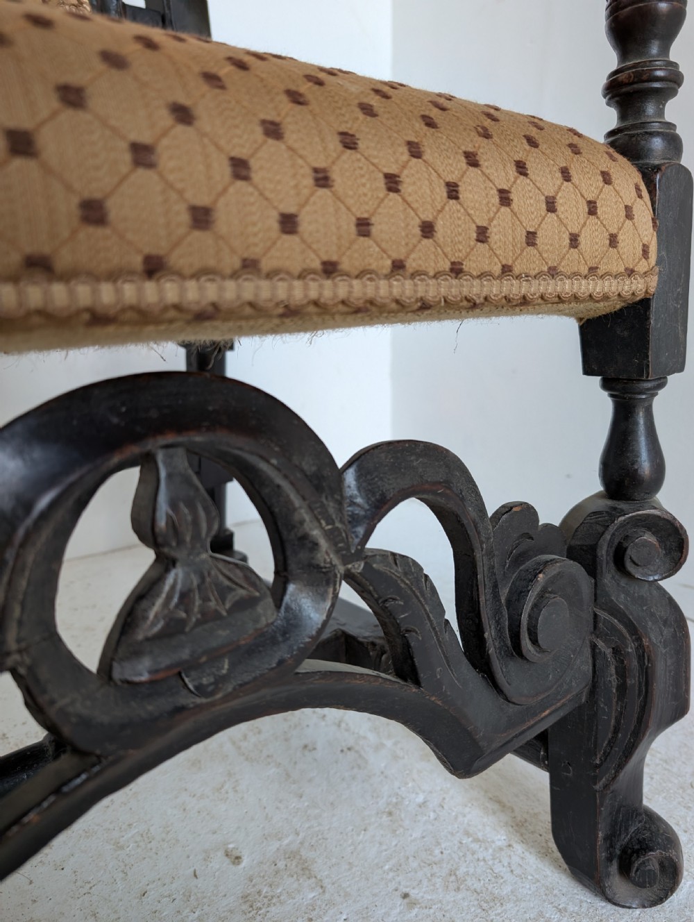 A late 17th-century William and Mary dark oak armchair featuring a tall carved crest rail, an upholstered back and seat in patterned fabric, and elaborate scrollwork stretchers. View II