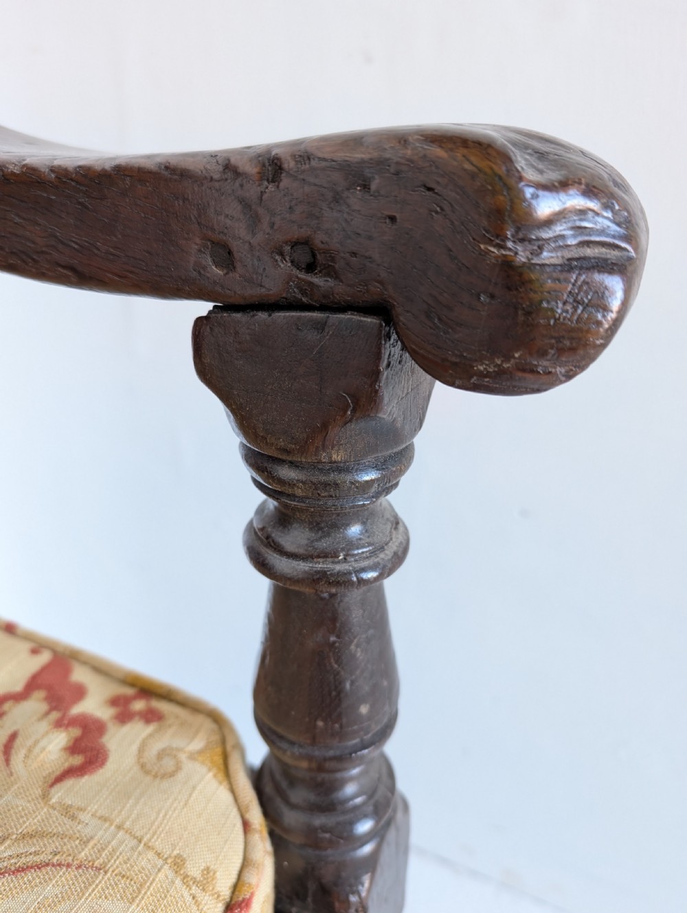 A dark oak 17th-century wainscot armchair featuring a panelled backrest, turned front legs, robust armrests, and an upholstered seat cushion. View VIII