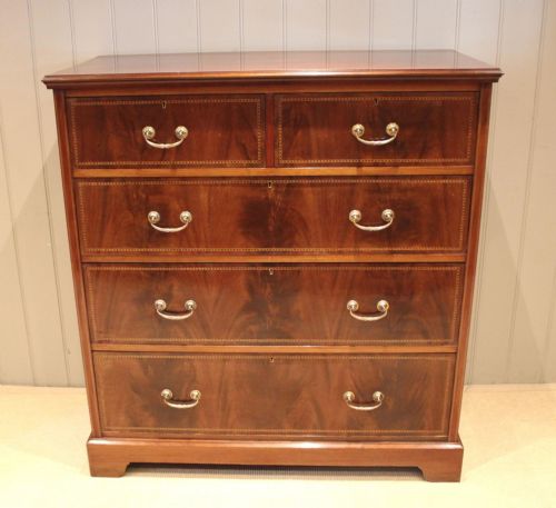 fig 1. An Edwardian mahogany chest of drawers featuring two short over three long drawers with decorative brass handles and subtle inlaid borders.