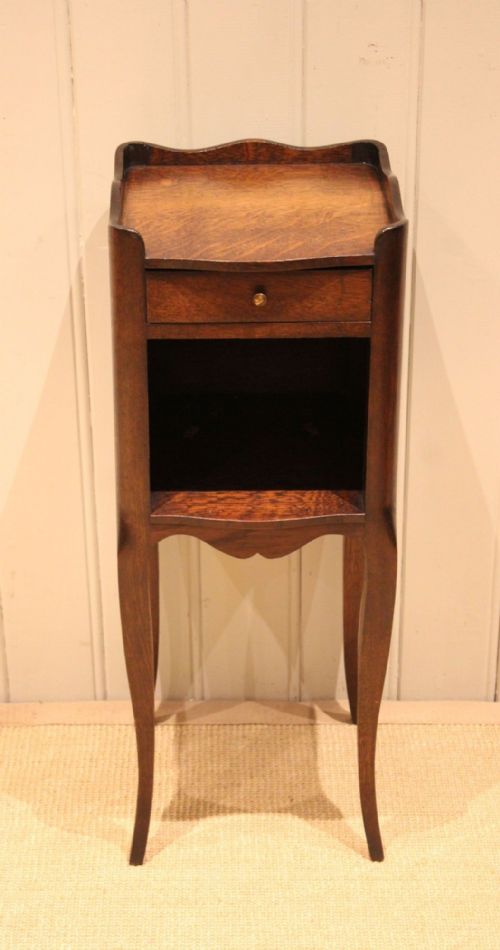 fig 1. A French dark oak bedside cabinet featuring a shaped tray top, single drawer, open compartment, pierced side cut-outs, and cabriole legs.