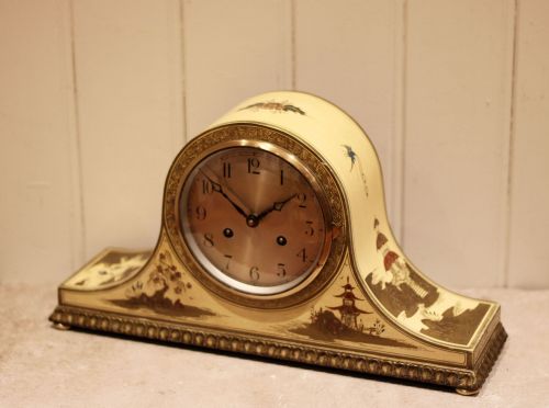 fig 2. An arched cream lacquered mantel clock featuring hand-painted Chinoiserie pagoda landscapes and a brass-rimmed dial with Arabic numerals.
