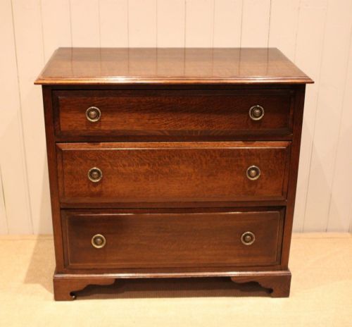 fig 1. A solid oak chest of drawers featuring three full-width drawers with circular brass drop ring handles and bracket feet.