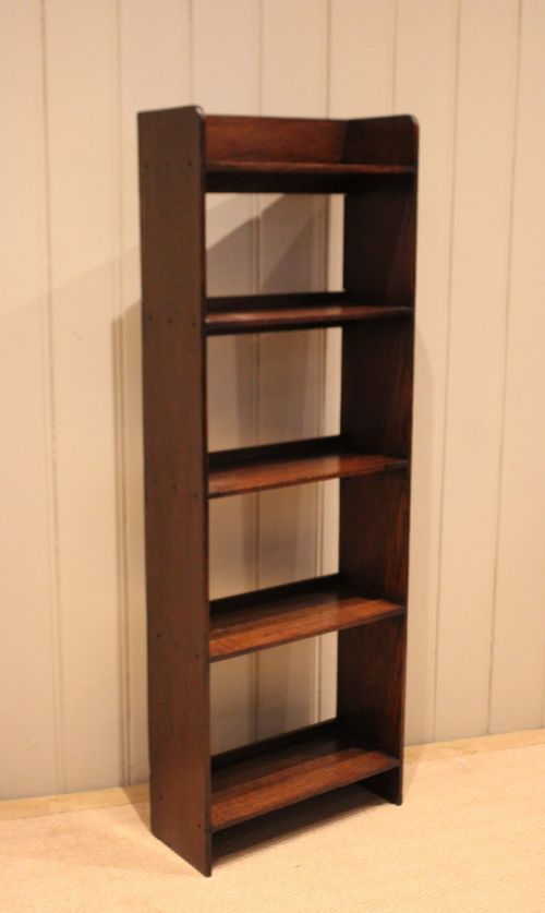 fig 1. A narrow 1920s dark oak open bookcase featuring four fixed shelves filled with vintage books.