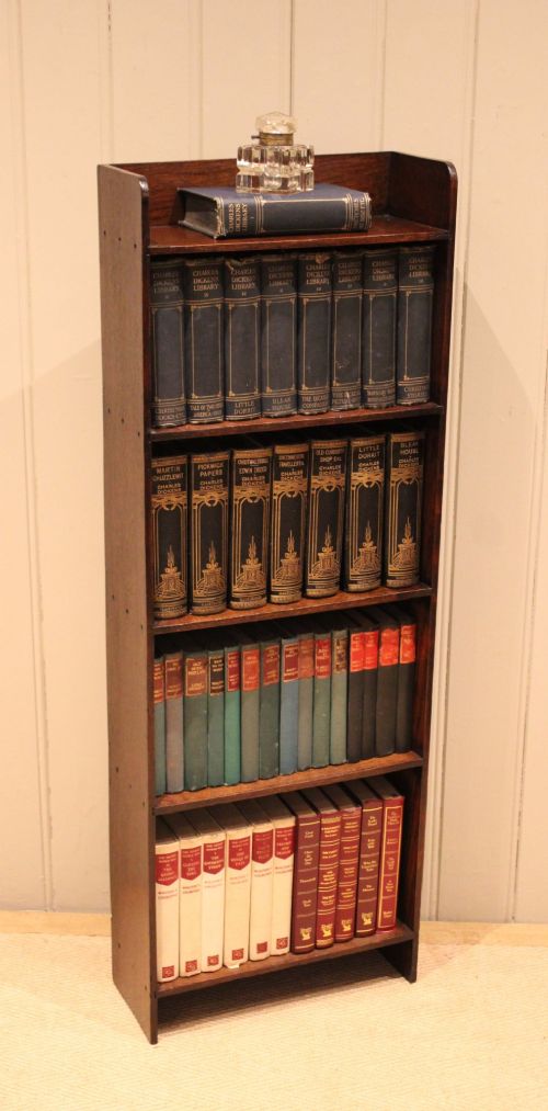 A narrow 1920s dark oak open bookcase featuring four fixed shelves filled with vintage books. View IX