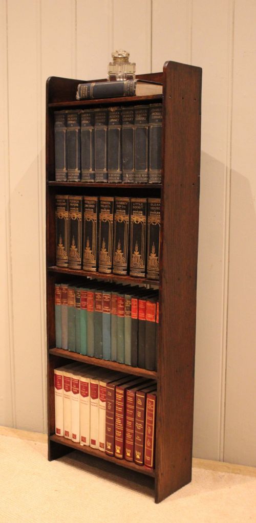 A narrow 1920s dark oak open bookcase featuring four fixed shelves filled with vintage books. View XI