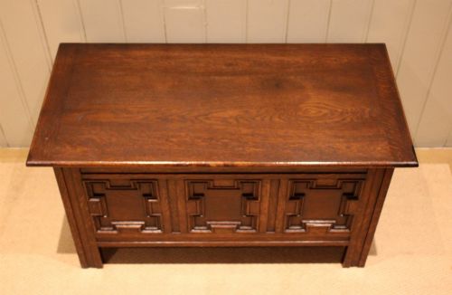 fig 1. A dark oak coffer featuring three carved geometric recessed panels across the front and a flat hinged top lid.