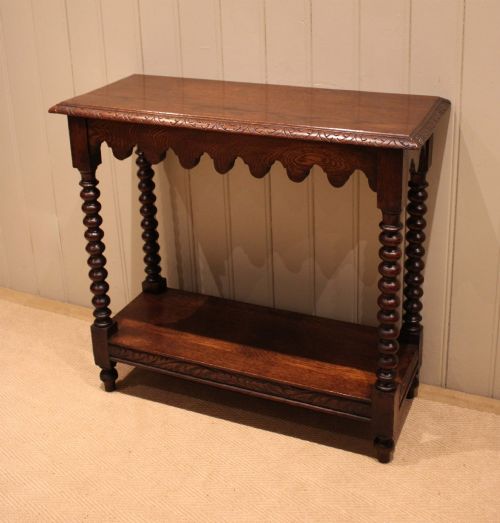 fig 1. A dark oak console table featuring a rectangular top with carved moulding, a scalloped apron, four bobbin-turned legs, and a lower tier shelf.