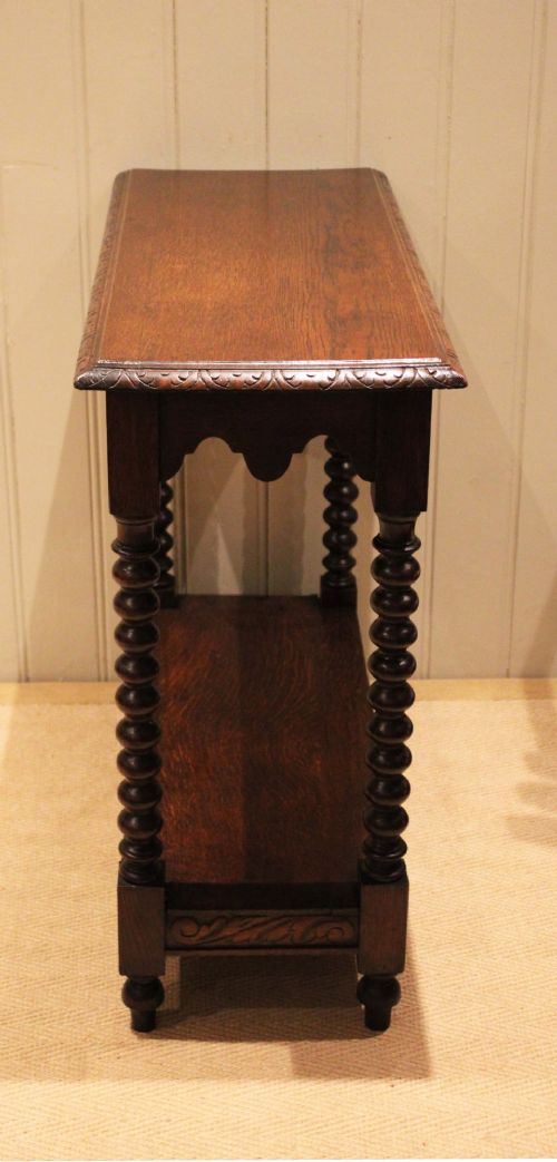 A dark oak console table featuring a rectangular top with carved moulding, a scalloped apron, four bobbin-turned legs, and a lower tier shelf. View VII