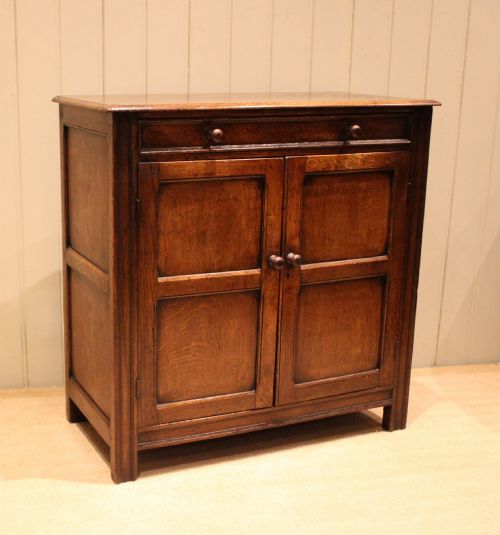 fig 1. A late nineteenth-century solid oak side cabinet featuring a single top drawer above two panelled cupboard doors with turned timber handles.