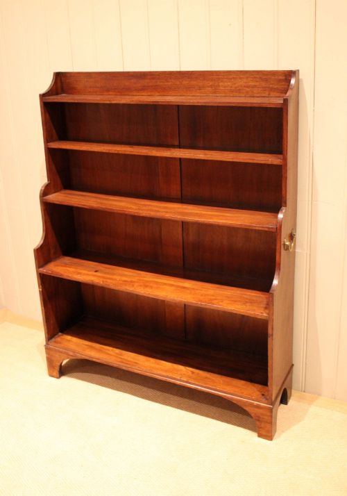 fig 1. An antique Regency mahogany open bookcase featuring four fixed shelves, graduated side panels, and a shaped apron base.
