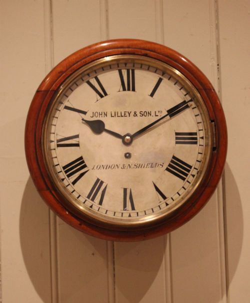 fig 1. A circular late nineteenth-century Victorian wall clock featuring a turned mahogany frame, a polished brass bezel, and a cream dial with black Roman numerals.