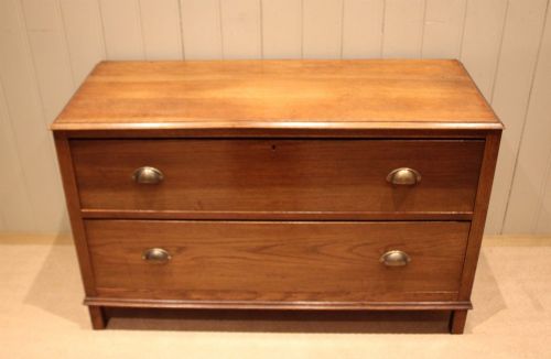 fig 1. A wide low oak chest of drawers featuring two deep drawers with brass shell cup handles and panelled side construction.