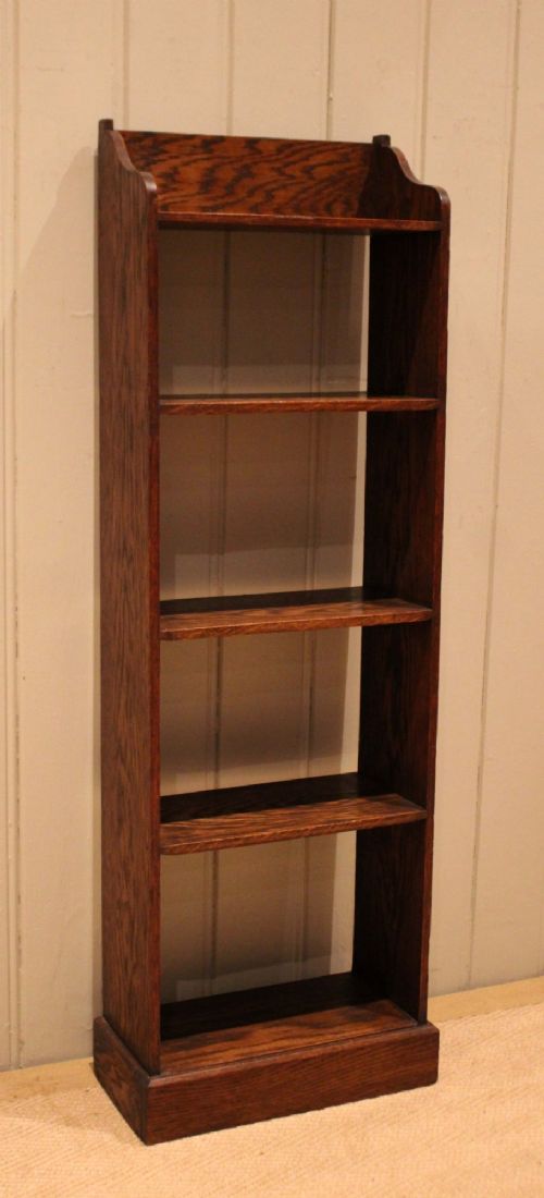 A tall, narrow dark oak open bookcase featuring multiple shelves, a shaped gallery top, and a solid plinth base. View VI