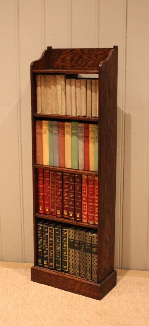 A tall, narrow dark oak open bookcase featuring multiple shelves, a shaped gallery top, and a solid plinth base. View VII