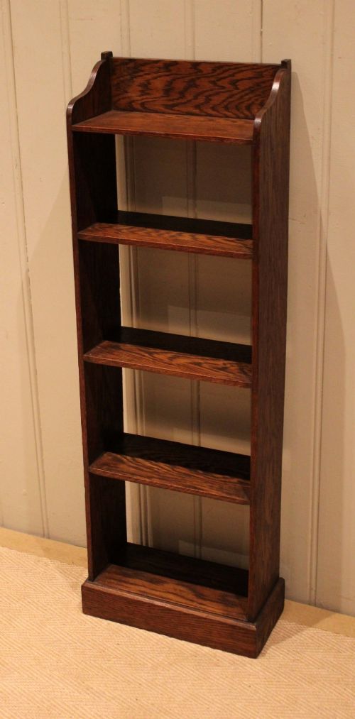 A tall, narrow dark oak open bookcase featuring multiple shelves, a shaped gallery top, and a solid plinth base. View VIII
