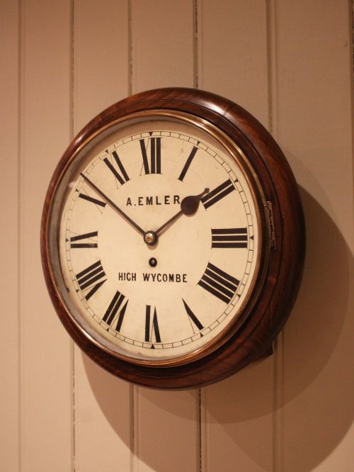 fig 1. An antique circular wall clock featuring a turned dark beech frame, brass bezel, and painted white dial with Roman numerals.