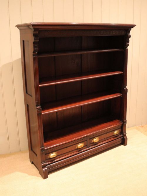 fig 1. A large late Victorian dark mahogany open bookcase featuring four tiered shelves and two lower drawers with brass cup handles.
