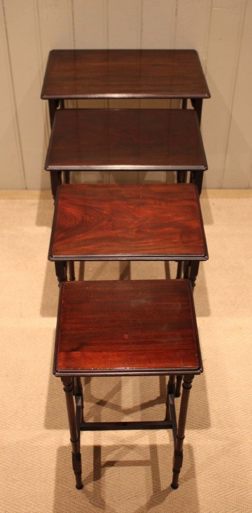 A set of four graduated mahogany nesting tables featuring rectangular tops with moulded edges, slender turned legs, and connecting stretchers. View VIII