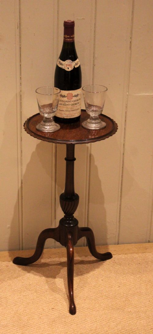 An Edwardian mahogany wine table featuring a scalloped piecrust circular top, a turned central stem, and three splayed tripod legs. View XI