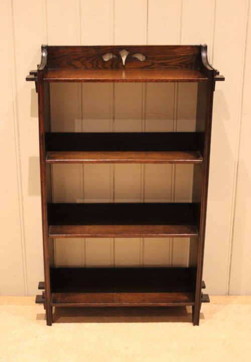 fig 1. A dark oak open bookcase featuring three shelves, protruding pegged side joints, and a shaped top gallery with a pierced motif.