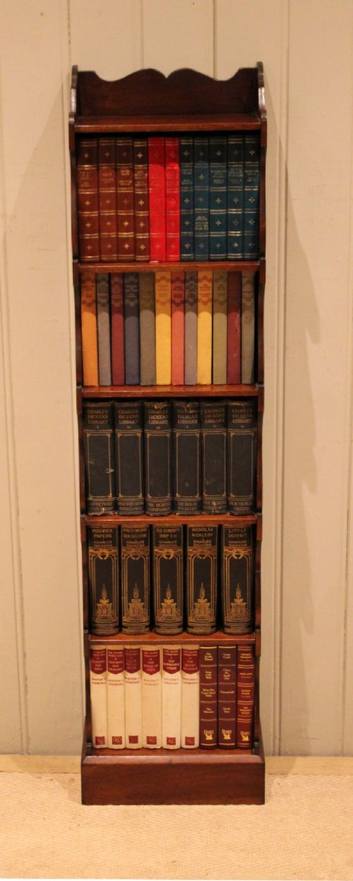 A tall and narrow dark mahogany open bookcase with five fixed shelves, shaped side aprons, and a scalloped top rail. View III