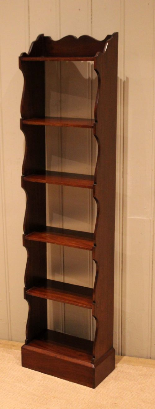 A tall and narrow dark mahogany open bookcase with five fixed shelves, shaped side aprons, and a scalloped top rail. View IV