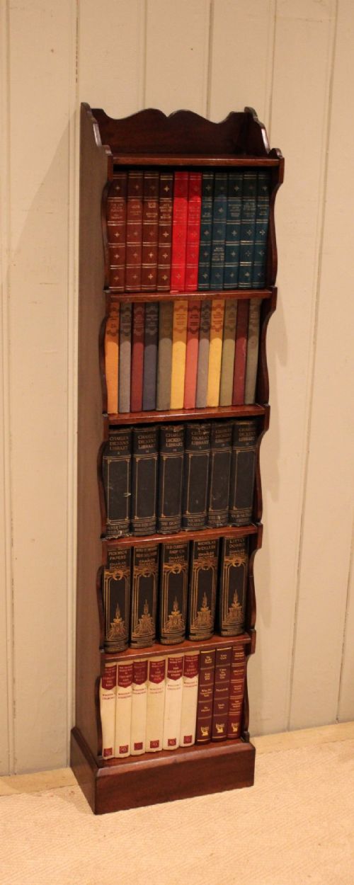 A tall and narrow dark mahogany open bookcase with five fixed shelves, shaped side aprons, and a scalloped top rail. View V