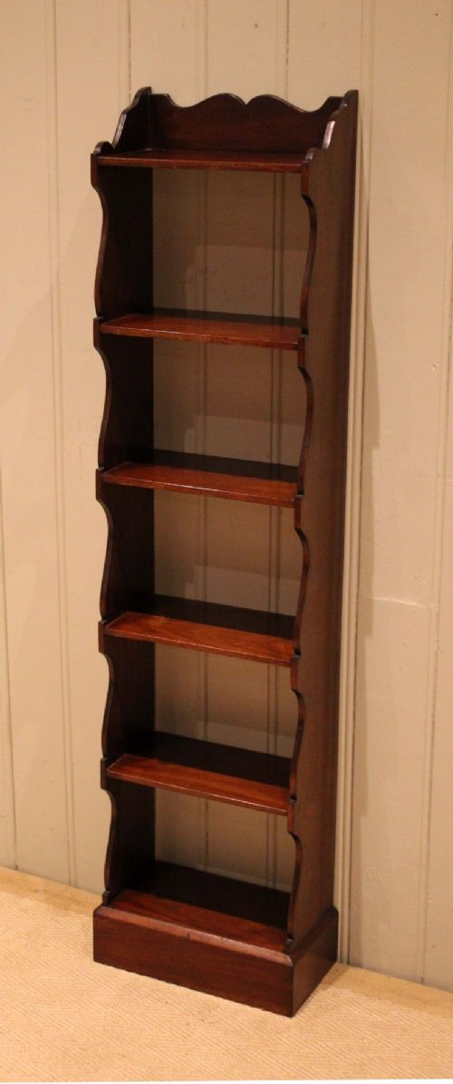 A tall and narrow dark mahogany open bookcase with five fixed shelves, shaped side aprons, and a scalloped top rail. View VI