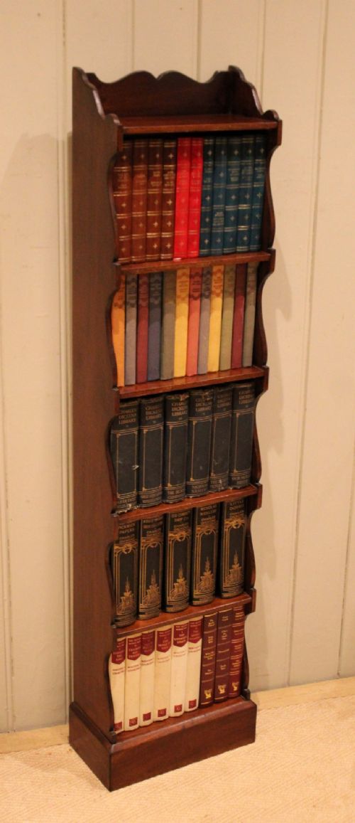 A tall and narrow dark mahogany open bookcase with five fixed shelves, shaped side aprons, and a scalloped top rail. View VII