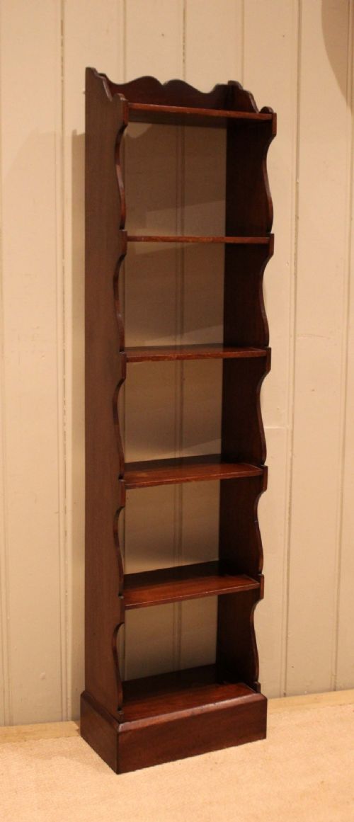 A tall and narrow dark mahogany open bookcase with five fixed shelves, shaped side aprons, and a scalloped top rail. View VIII
