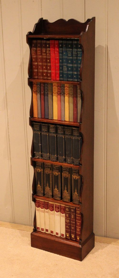A tall and narrow dark mahogany open bookcase with five fixed shelves, shaped side aprons, and a scalloped top rail. View IX