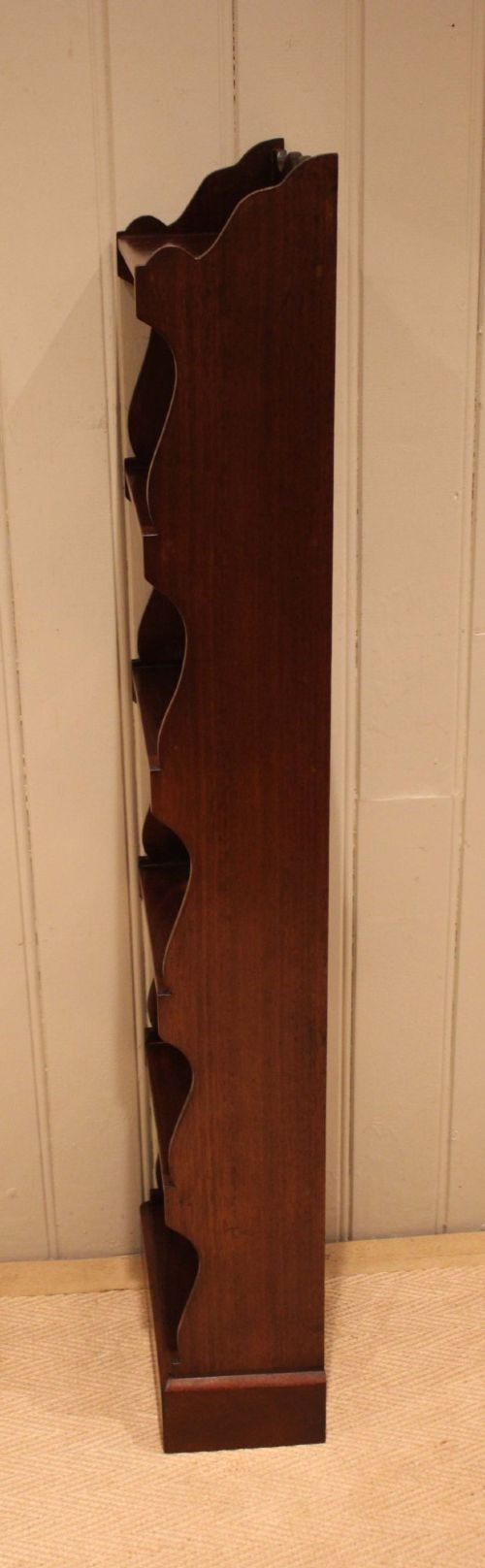 A tall and narrow dark mahogany open bookcase with five fixed shelves, shaped side aprons, and a scalloped top rail. View XI