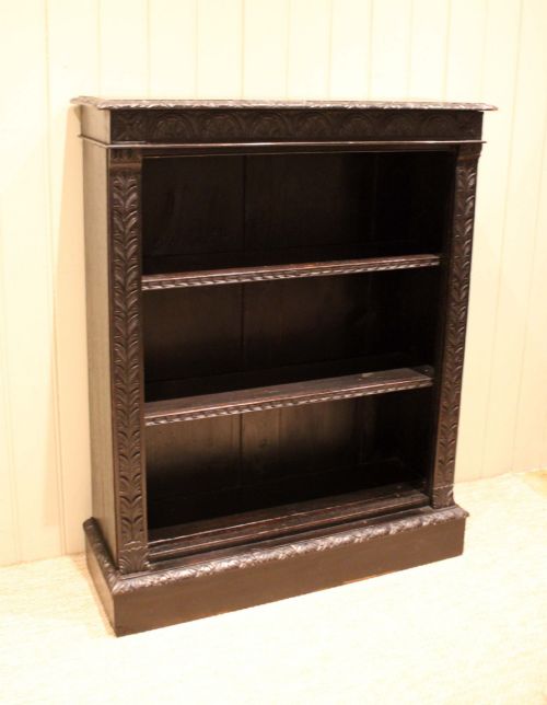 fig 1. A mid-Victorian dark oak open bookcase featuring hand-carved leaf mouldings and three open shelves filled with antique books.
