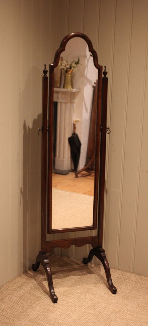 A mahogany cheval dressing mirror with an arched top frame, turned finials on the uprights, and splayed legs. View IV