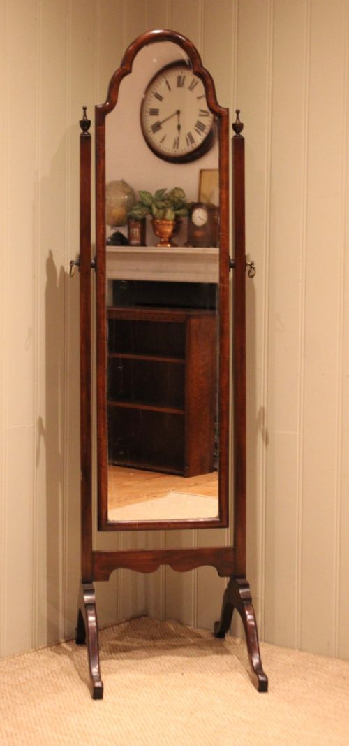 A mahogany cheval dressing mirror with an arched top frame, turned finials on the uprights, and splayed legs. View V