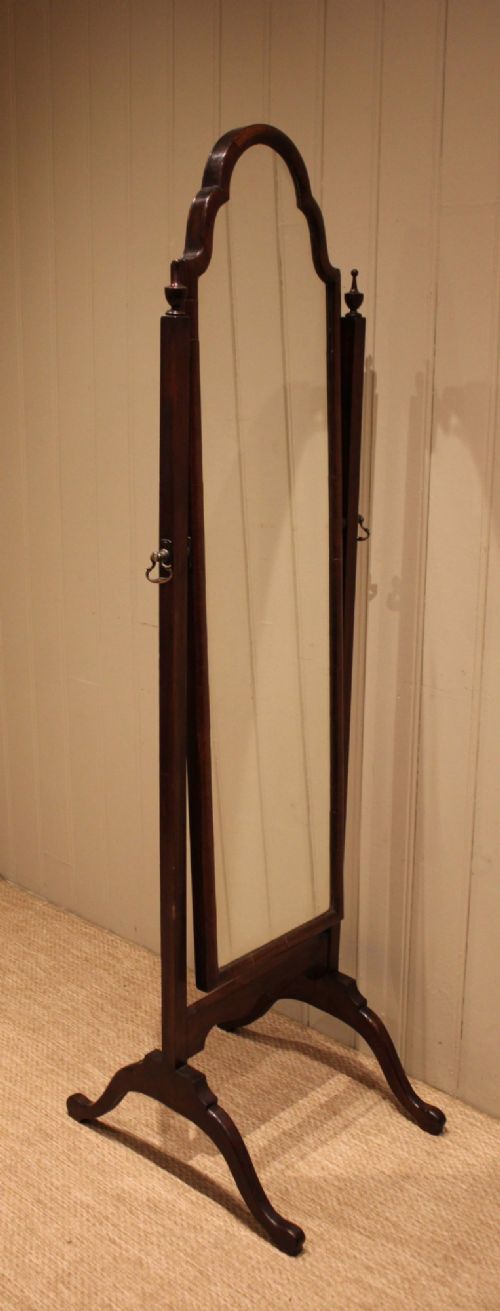 A mahogany cheval dressing mirror with an arched top frame, turned finials on the uprights, and splayed legs. View VII