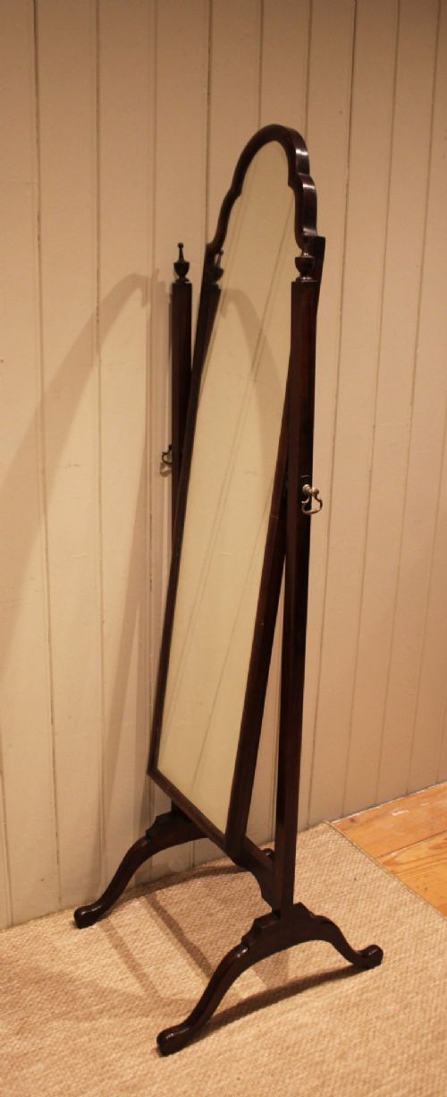 A mahogany cheval dressing mirror with an arched top frame, turned finials on the uprights, and splayed legs. View IX