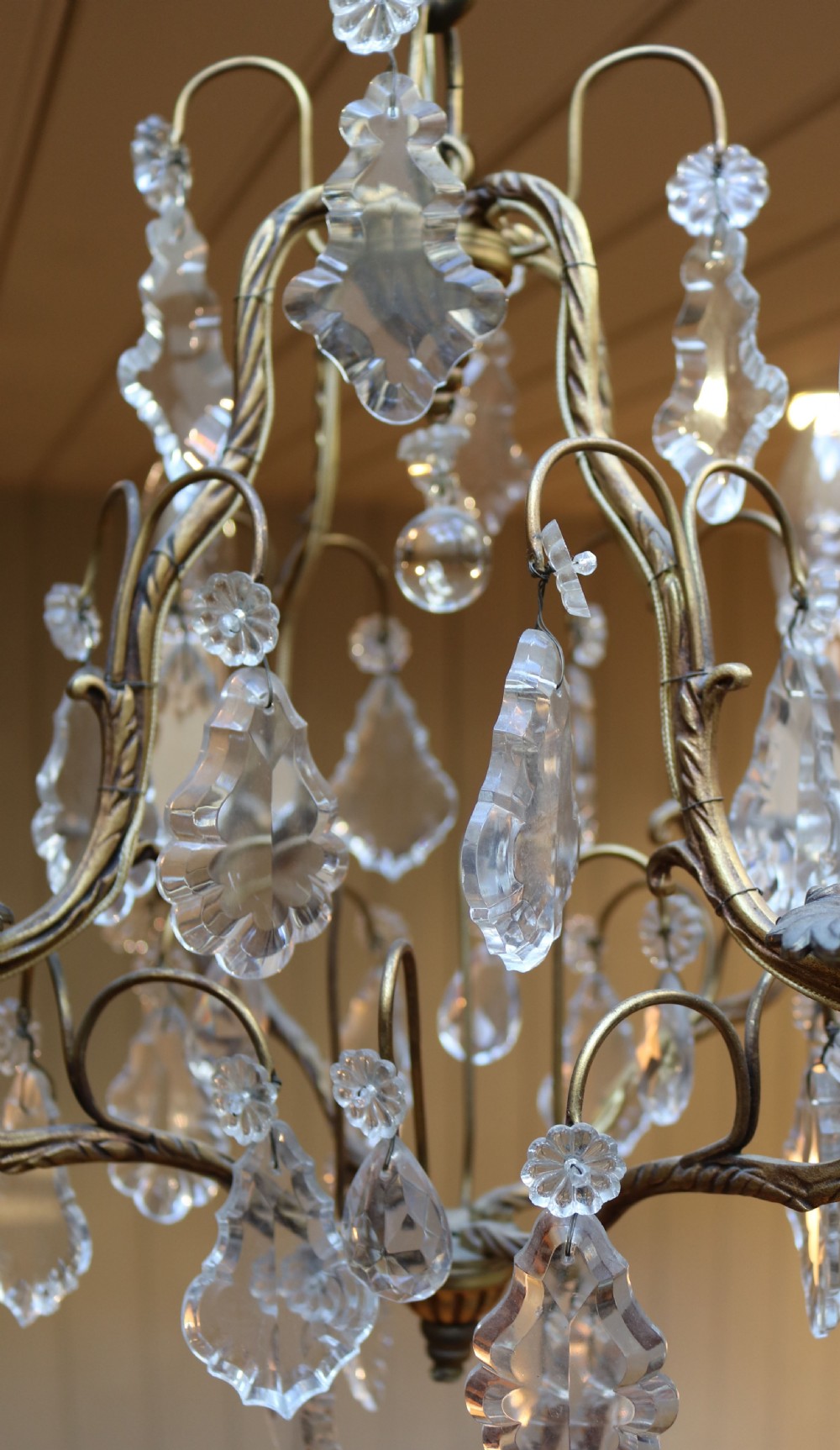 A French four-branch gilt metal chandelier adorned with clear cut glass crystal drops and faux candle sleeve light fittings. View VII