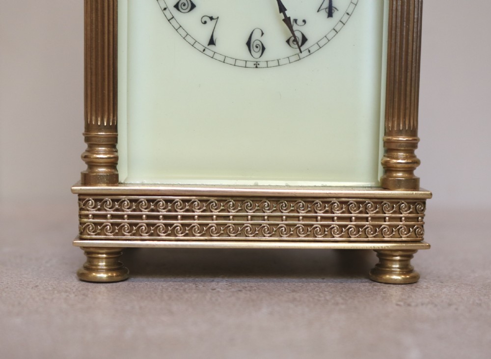 An Edwardian brass carriage clock featuring bevelled glass panels, fluted corner columns, a folding top handle, and a white dial with Arabic numerals. View VIII