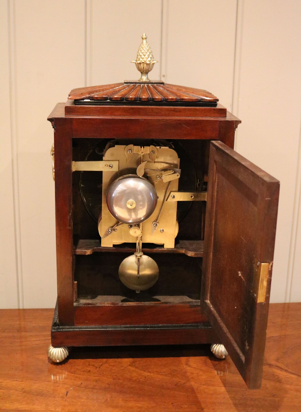 A Regency flame mahogany bracket clock with detailed brass inlay, a white circular dial signed Harris Brixton, side ring handles, and a brass pineapple finial. View V