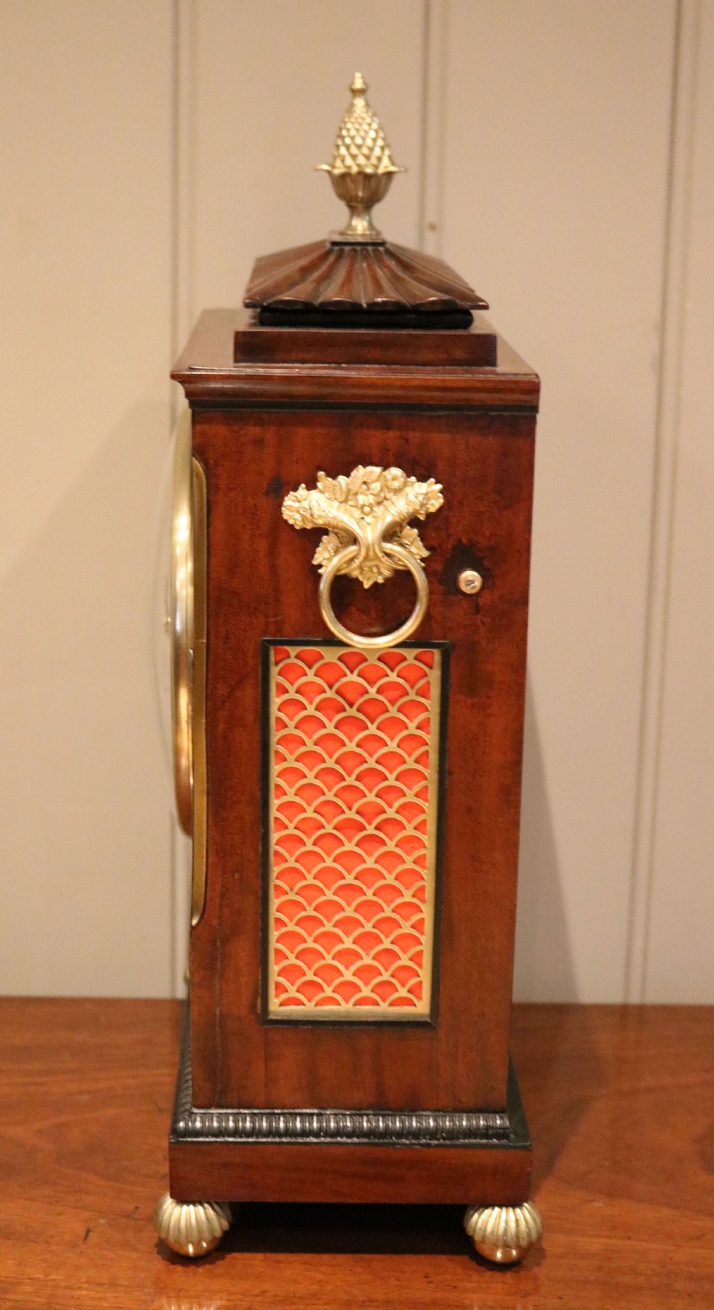 A Regency flame mahogany bracket clock with detailed brass inlay, a white circular dial signed Harris Brixton, side ring handles, and a brass pineapple finial. View VIII