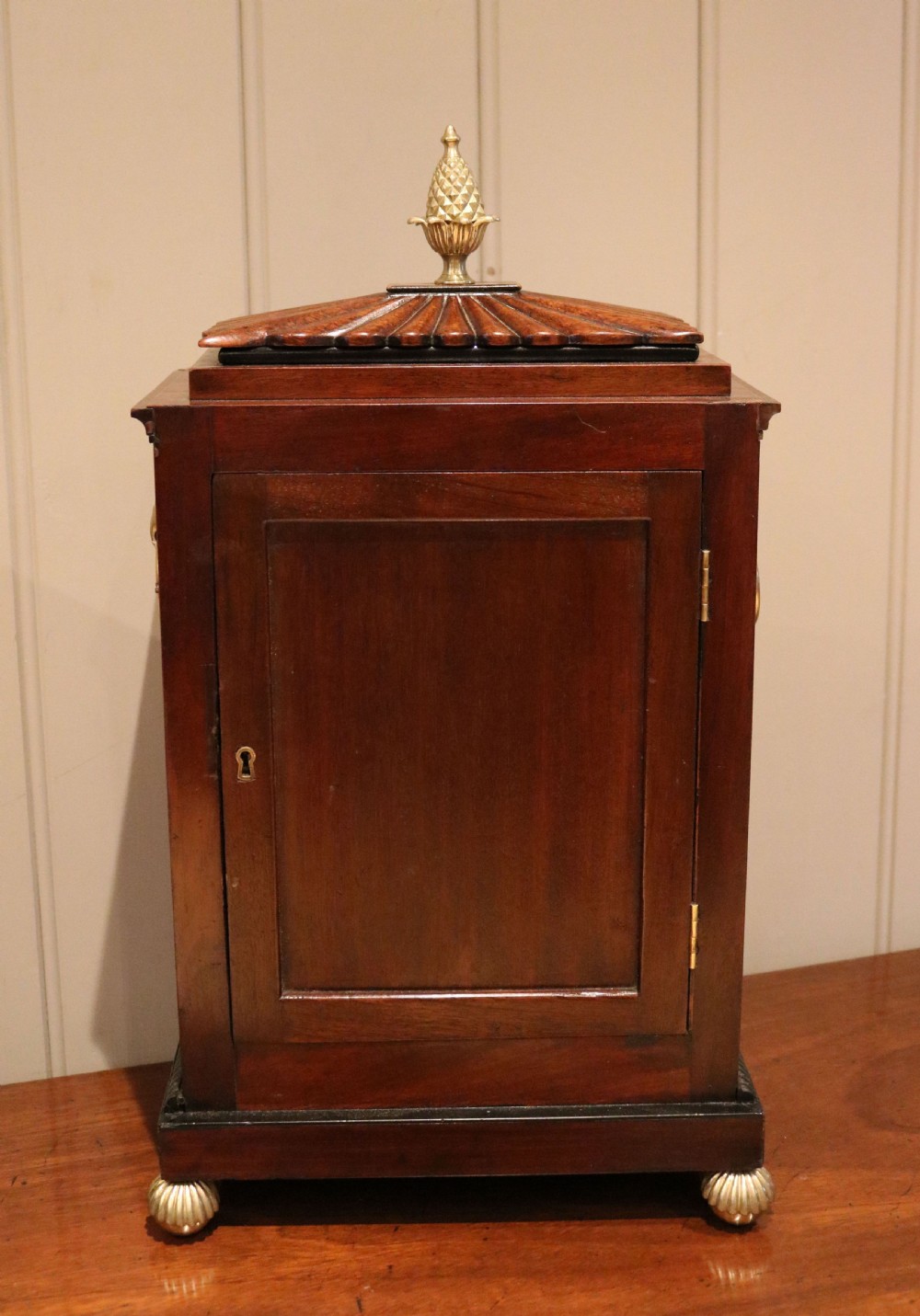 A Regency flame mahogany bracket clock with detailed brass inlay, a white circular dial signed Harris Brixton, side ring handles, and a brass pineapple finial. View XIV