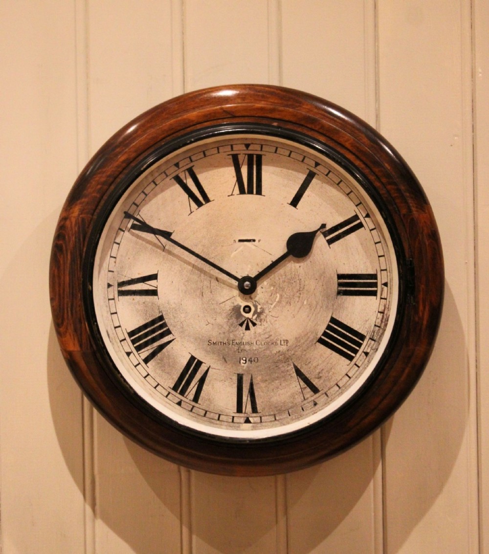 A circular 1940s wall clock featuring a turned beech wood bezel surround and an aged dial with black Roman numerals.